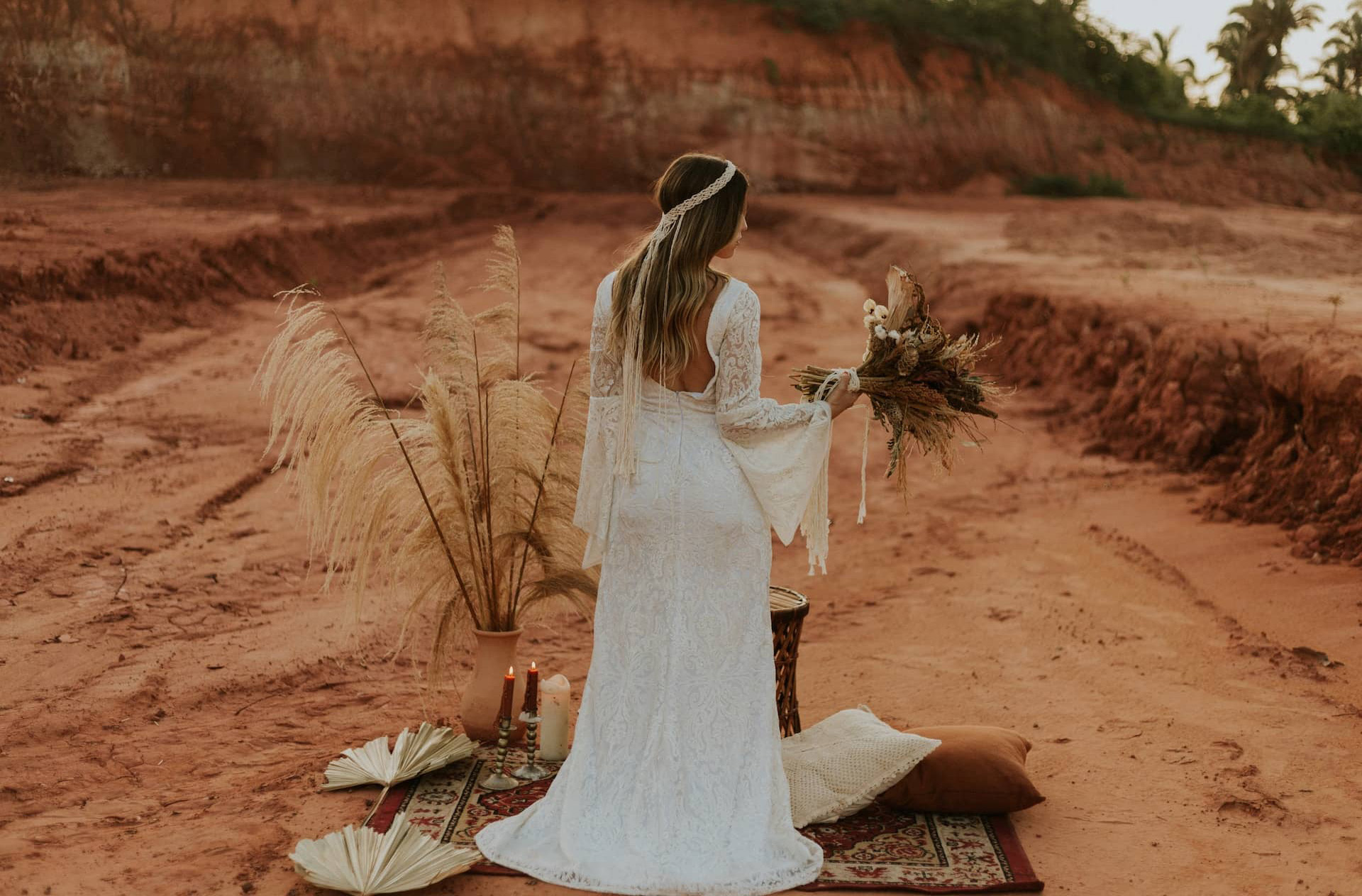 woman in wedding dress holding boquet standing on a rug in the desert