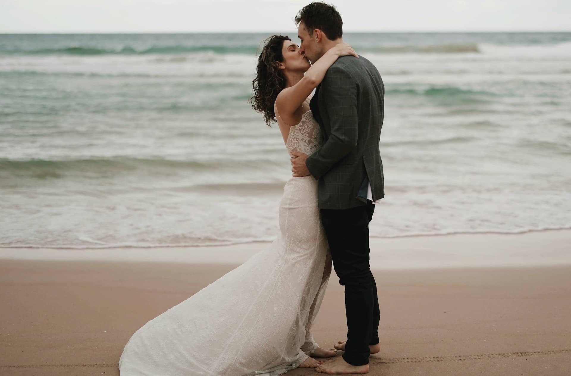 bride and groom kissing on the beach